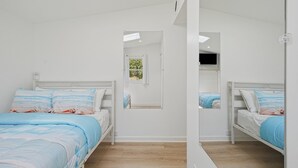 Een slaapkamer met twee bedden, een raam en een spiegel.