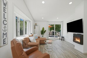A modern living room with a sofa, a TV, and a fireplace.
