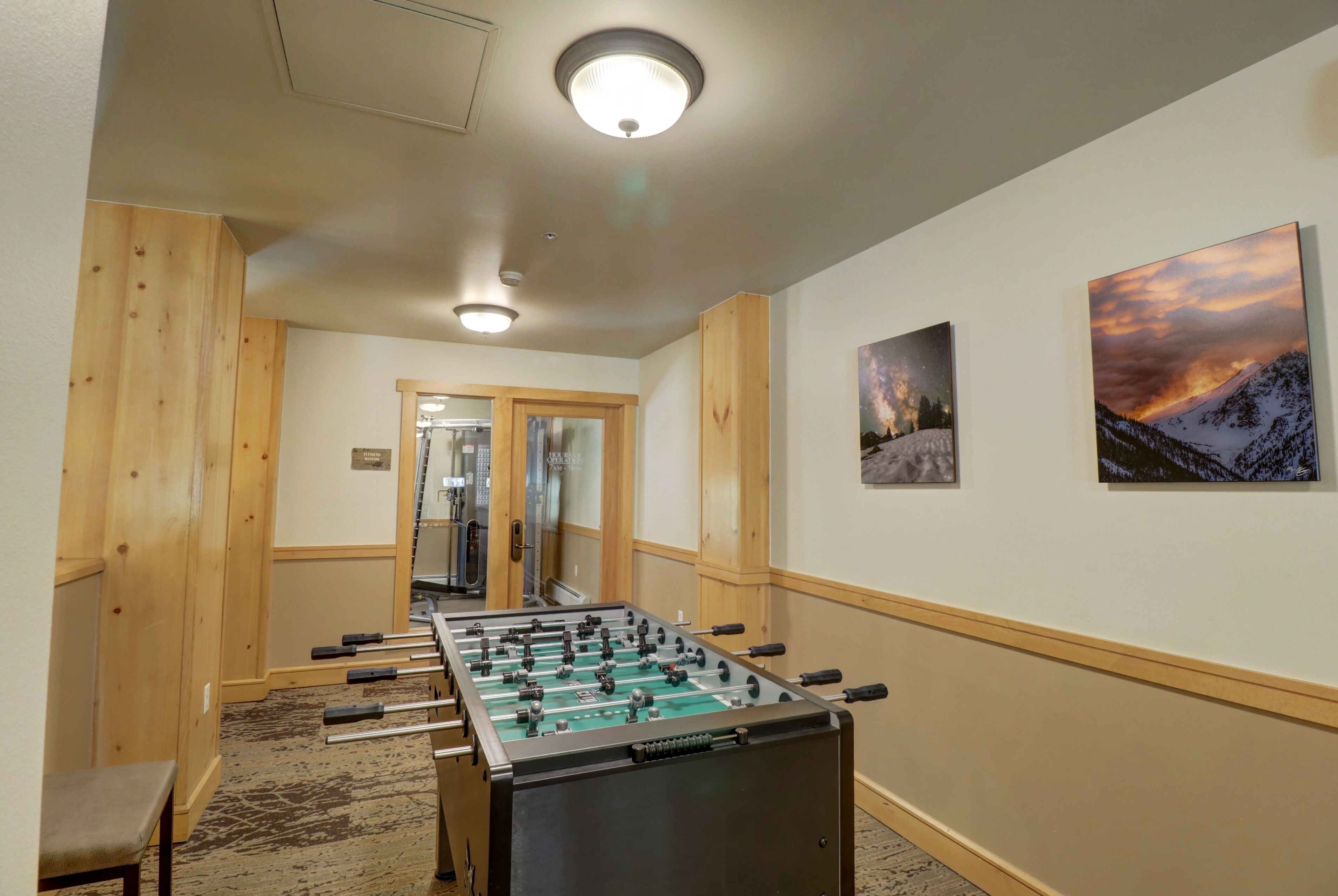 Une pièce avec une table de baby-foot, des lambris en bois et deux tableaux encadrés au mur.