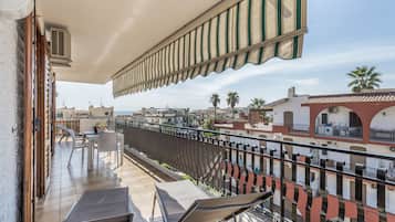 Un balcon avec une table et des chaises, un auvent à rayures et une vue sur le paysage urbain.