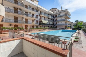 A multi-story residential building with a swimming pool, balconies, and a brick pathway. - Apartment 'Naxos Sea View' with Sea View, Wi-Fi and Air Conditioning (Naxos)