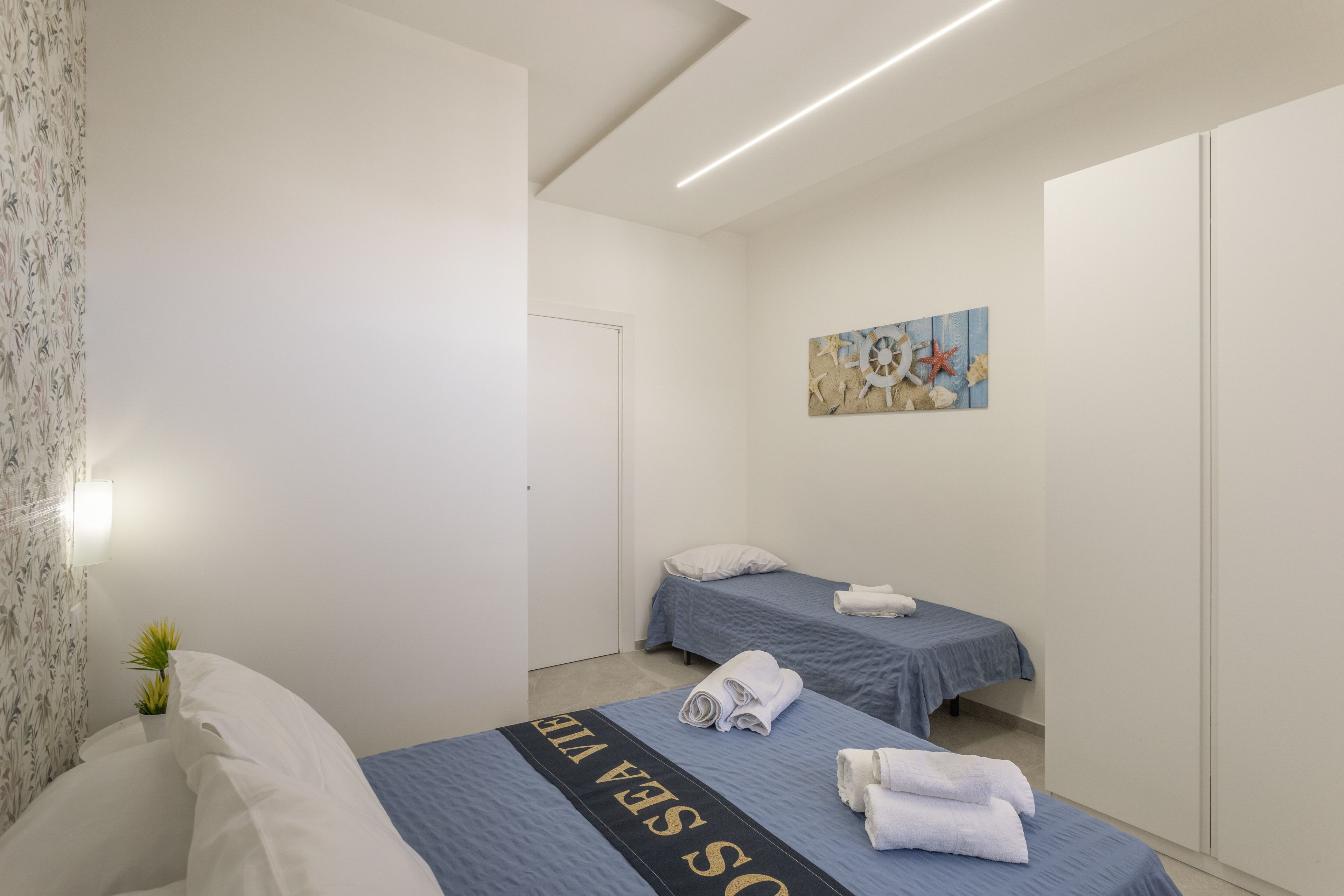 Ein Hotelzimmer mit zwei Betten, einem Bild an der Wand und einem Blumentopf.