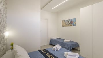 Une chambre d’hôtel avec deux lits, un tableau au mur et une plante en pot.