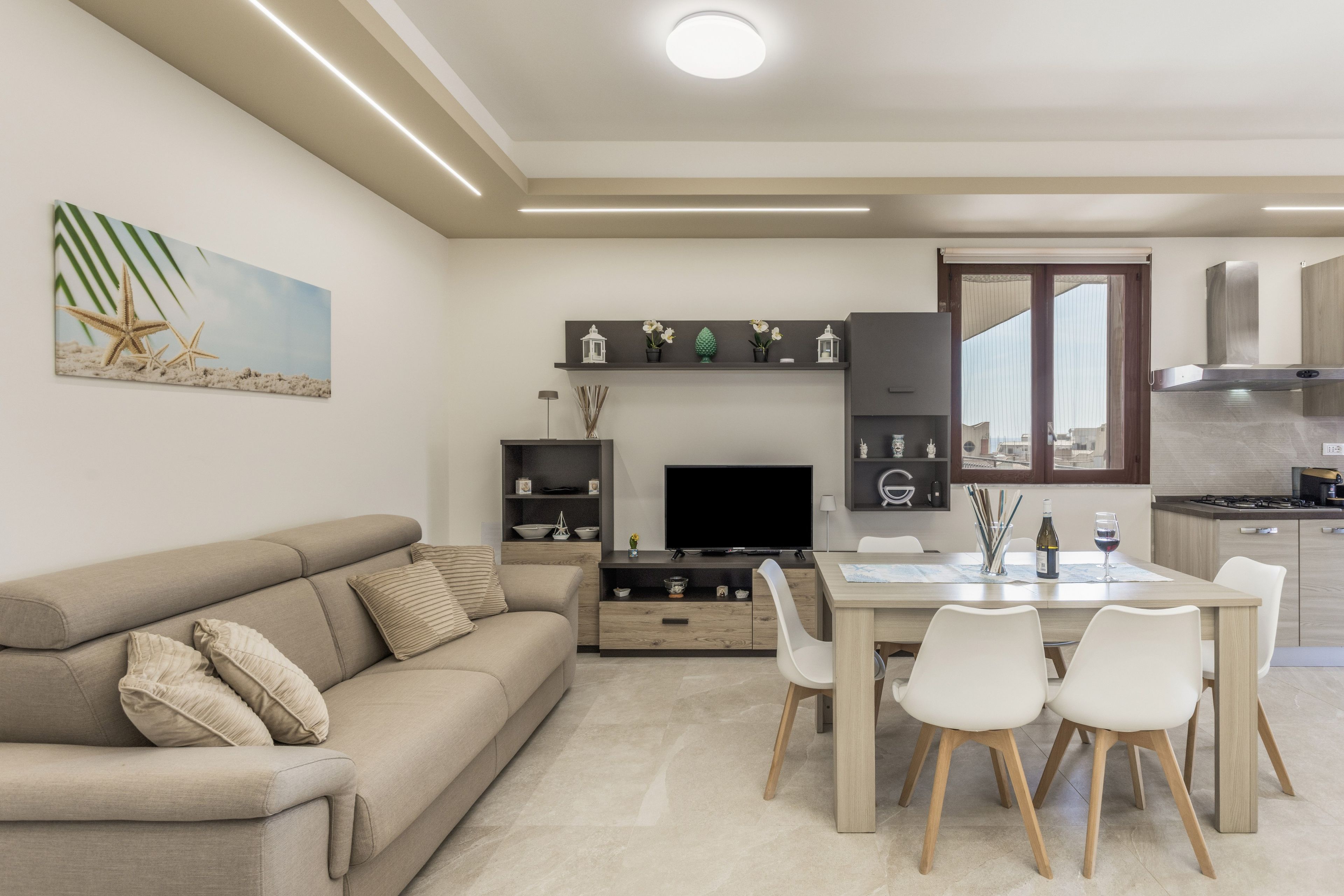 A modern living room with a sofa, TV, and dining area with chairs and a table.