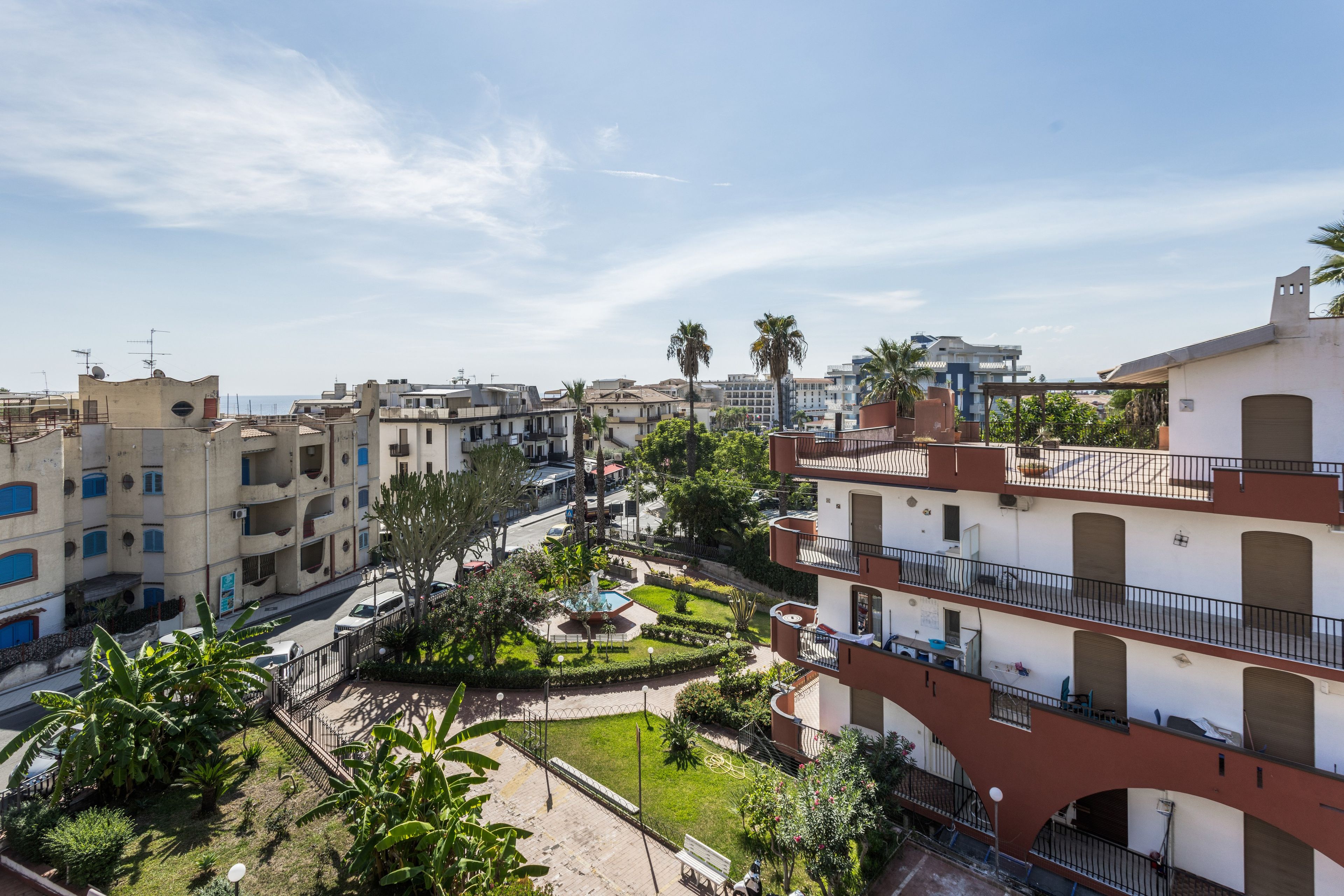 Un quartier résidentiel avec des immeubles à plusieurs étages, une cour centrale dotée d’une fontaine et un ciel dégagé.
