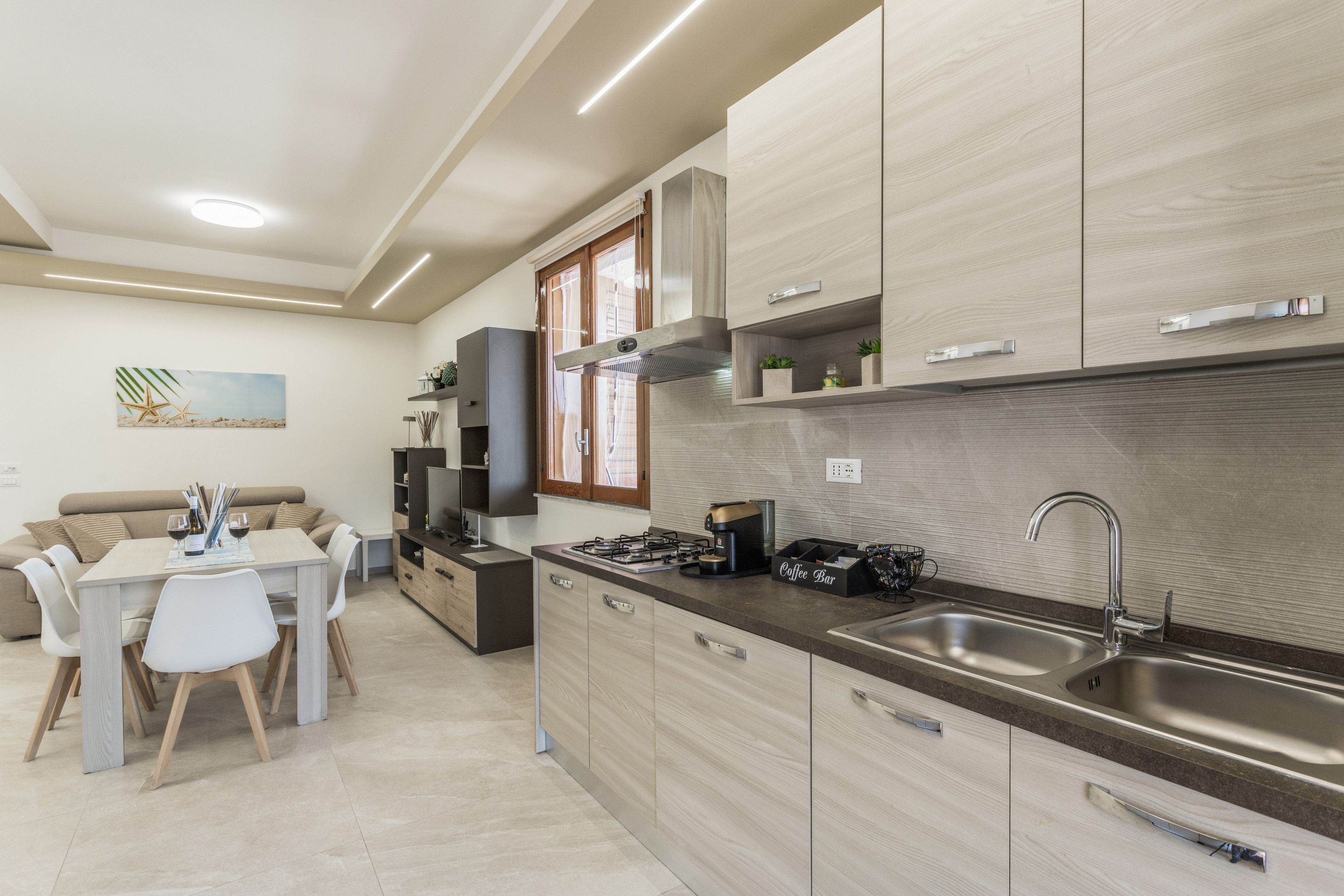 Une cuisine moderne équipée d’une cuisinière intégrée, d’un évier et d’une machine à café. On y trouve également un coin repas avec une table et des chaises.