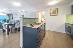 Eine moderne Küche mit Essbereich, Blick ins Freie und einer kleinen Kücheninsel mit Spüle.