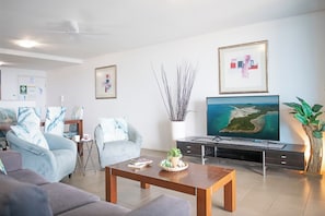 Ein modernes Wohnzimmer mit Flachbildfernseher, Couchtisch und Sofa.