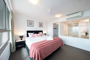 Ein Hotelzimmer mit Bett, Nachttischen, einem Spiegel, einer Klimaanlage und Blick ins Bad.
