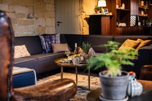 A cozy living room with a sofa, a coffee table with drinks and flowers, and a bookshelf in the background.