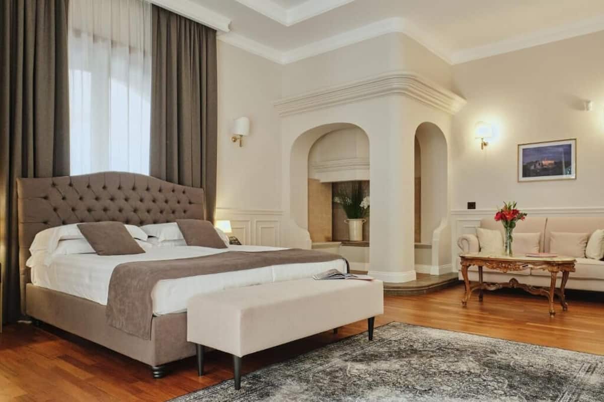 A bedroom with a large bed, a sofa, a coffee table, and a painting on the wall.