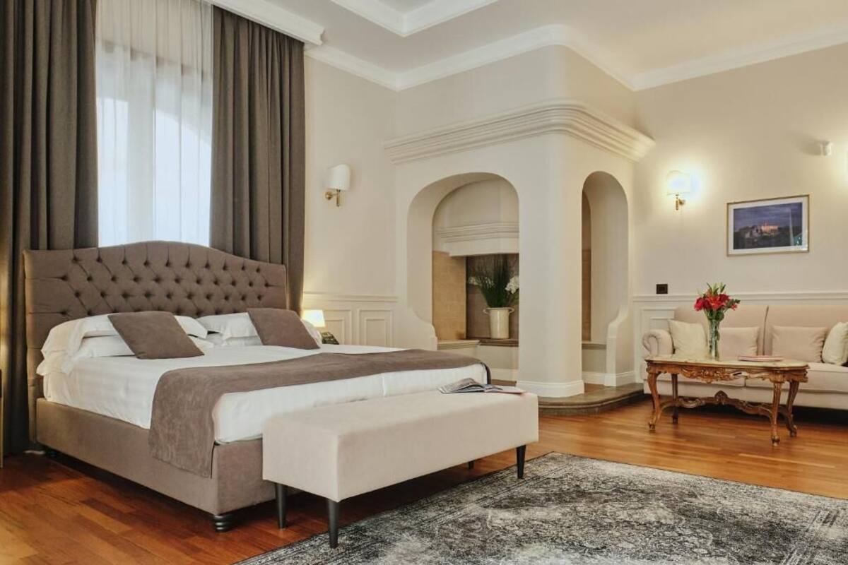 Un dormitori amb un llit gran, un sofà, una taula de cafè i un quadre a la paret.