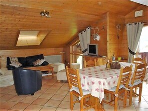 A cozy cabin interior with a dining table, chairs, a sofa, and a television. - 100m from ski slopes, 3rd floor, balcony, tv, 74m², Pralognan-la-Vanoise (Pralognan-la-Vanoise)
