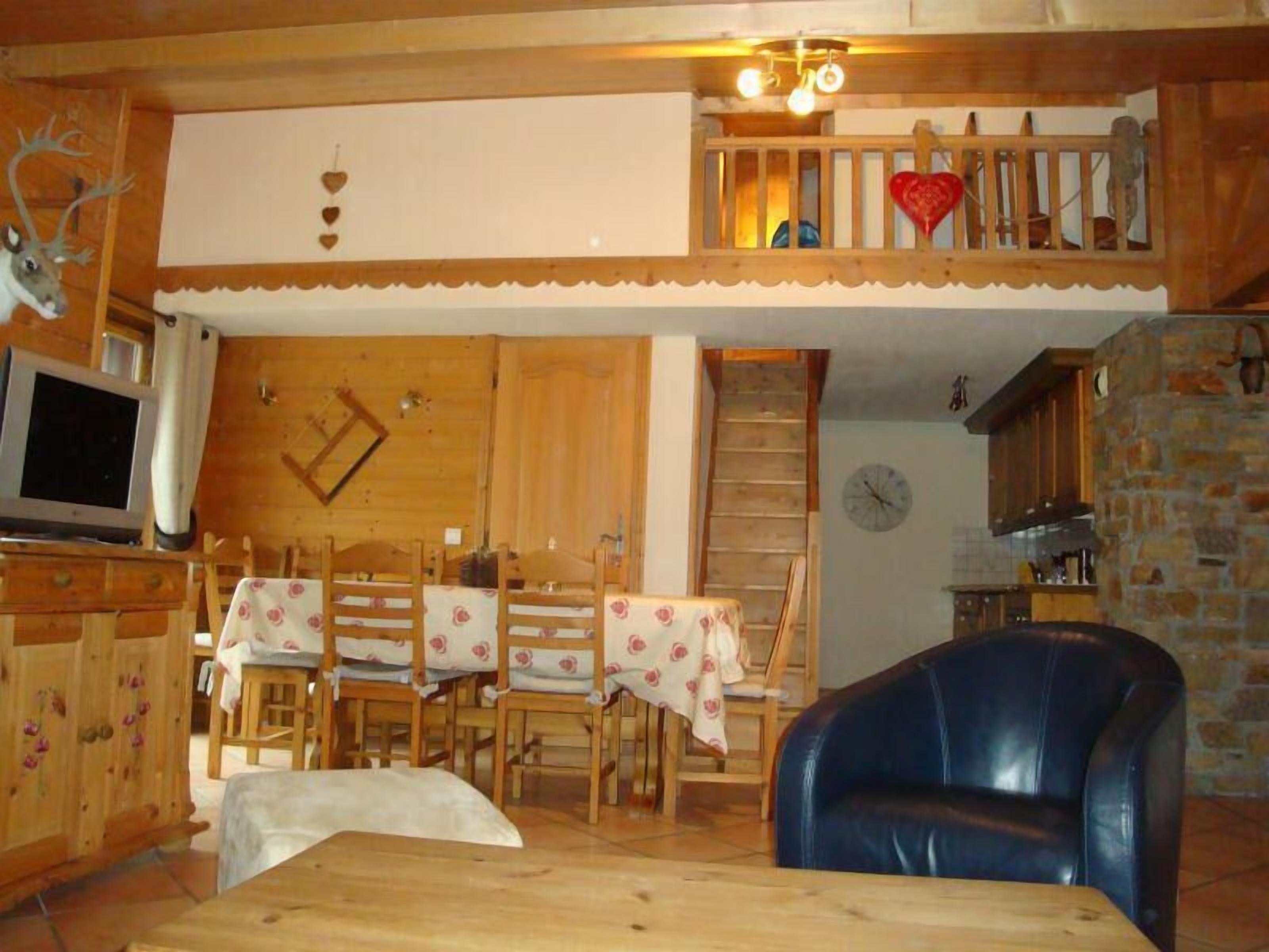 Un comedor de madera con una mesa y sillas, un televisor y una pared de piedra.