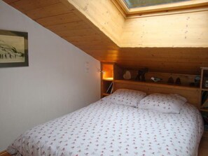 A bedroom with a bed, a skylight, a wall-mounted shelf with items, and a framed picture. - 100m from ski slopes, 3rd floor, balcony, tv, 74m², Pralognan-la-Vanoise (Pralognan-la-Vanoise)