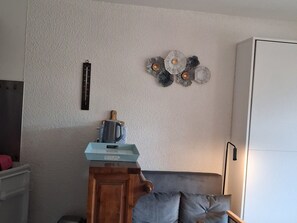 Um quarto com um armário de madeira, um sofá cinza, um objeto decorativo na parede e um armário branco.