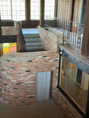 A multi-level brick structure with a metal railing, a staircase, and a glass enclosure.