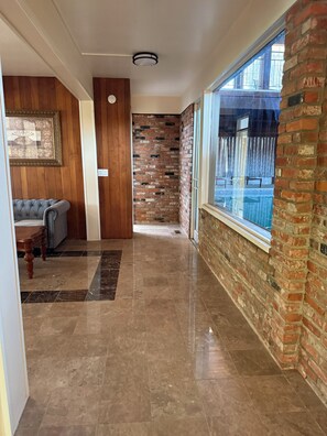 A hallway with a brick wall, a large window, and a wooden wall with a framed picture.