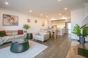 Un salon moderne comprenant un canapé, des fauteuils, une table basse et un coin repas.