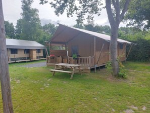 Ein Campingplatz mit Holzterrasse, Picknicktisch und einer zeltartigen Konstruktion.