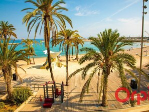 A beach with palm trees, a wooden deck, and a view of the sea.