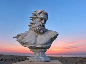 Eine Brustbüste auf einem Sockel mit blauem Himmel und Sonnenuntergang im Hintergrund.