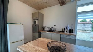 Eine kleine Küche mit Holztisch, Drahtkorb, Mikrowelle, Spüle und Geschirrspüler.