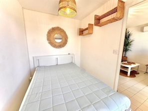 Ein Schlafzimmer mit einem Bett, einem Wandspiegel und Korbschrankregalen.
