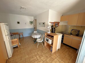 A compact kitchen with a dining table, chairs, a refrigerator, and a microwave. - Cozy apartment with pool - 3 guests (Argelès-sur-Mer)