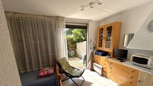Een kleine keuken met een magnetron, een televisie en een houten kast.