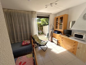 A compact kitchen with a microwave, a television, and a wooden cabinet. - Cozy apartment with pool - 3 guests (Argelès-sur-Mer)