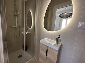 A modern bathroom with a glass shower enclosure, a freestanding sink, and a large mirror with a circular frame. - Penthouse with panoramic cathedral view - 6 guests (Málaga)