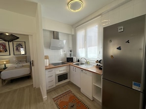 A modern kitchen with white cabinetry, a stainless steel refrigerator, a microwave, and a sink. - Penthouse with panoramic cathedral view - 6 guests (Málaga)