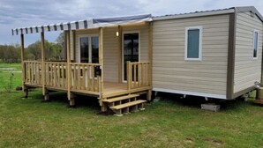 Ein Wohnmobil mit einer Holterrasse und einer überdachten Veranda.