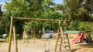 A playground with a swing set, a slide, and a climbing structure. - Mobile home - 6 guests, pets welcome (Séez)
