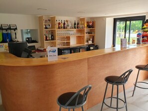 Eine Bar mit einer Theke, Hockstühlen und Regalen voller Flaschen und Gläsern.