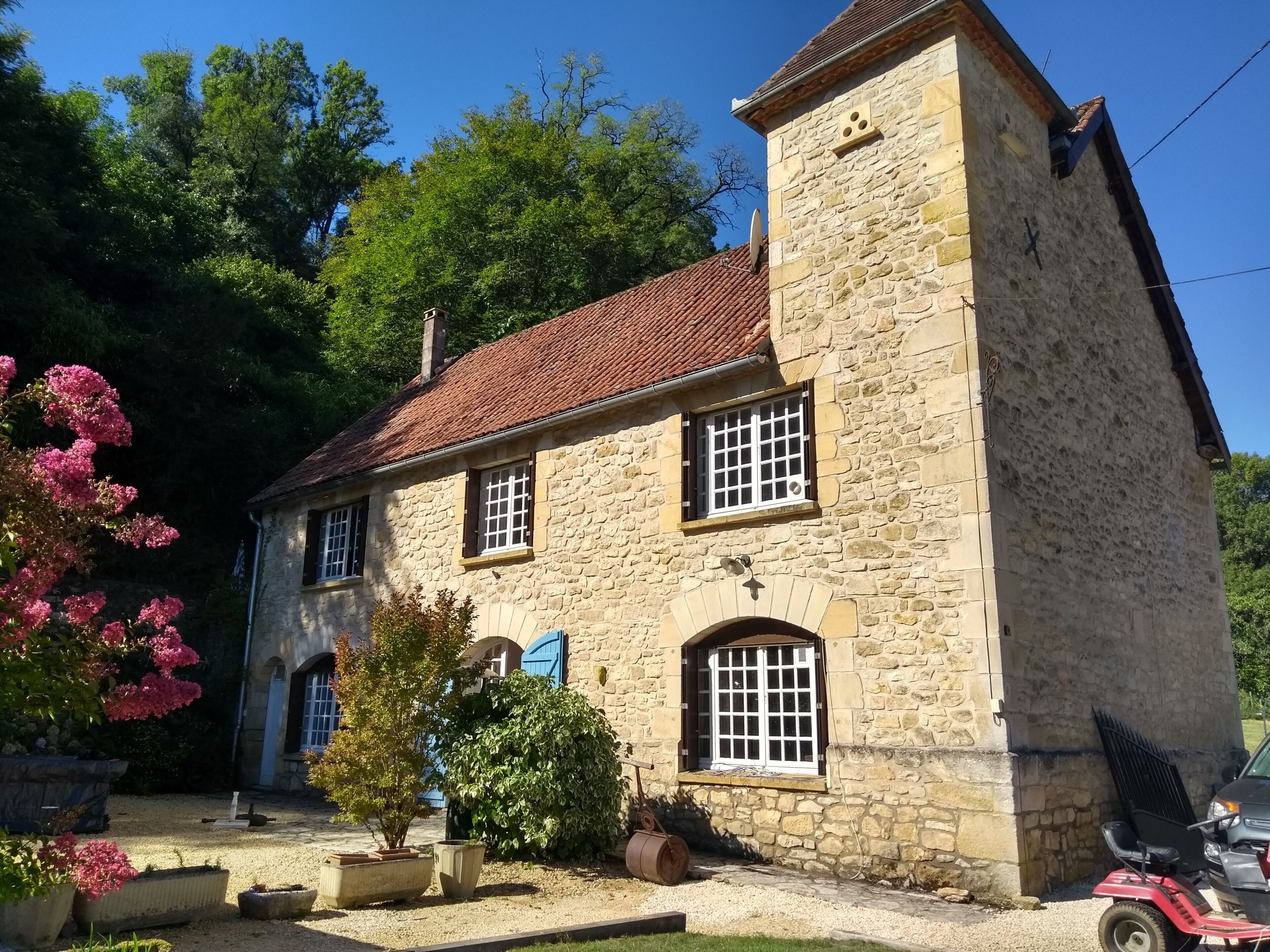 Un bâtiment en pierre avec un toit recouvert de tuiles rouges, de nombreuses fenêtres et une antenne parabolique.