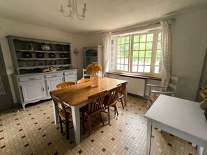 Ein Essbereich mit Holztisch und Stühlen, einer weißen Kommode mit Geschirr und einem fenster mit Vorhängen.