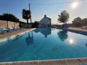 A clear swimming pool with lounge chairs and a building in the background. - Mobile home with terrace - 4 guests (Ambon)