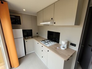 A compact kitchen with a gas stove, a coffee maker, and a refrigerator. - Mobile home with terrace - 4 guests (Ambon)