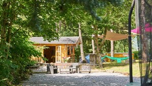 A rustic cabin with a gravel path leading to a wooden deck, surrounded by trees.