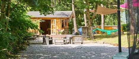 A rustic cabin with a gravel path leading to a wooden deck, surrounded by trees.