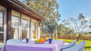 An outdoor dining area with a checkered tablecloth, chairs, a vase with flowers, and a view of the surrounding landscape. - Rural Charm Near the Sea: Casa Íntegra in Ajo (Bareyo)