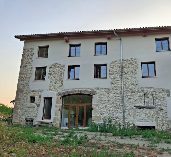 A multi-story building with a stone facade, multiple windows, and a central entrance with glass doors.