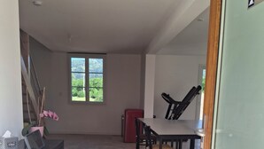 Une pièce spacieuse comprenant un coin repas, un petit réfrigérateur rouge et une fenêtre donnant sur un paysage verdoyant.
