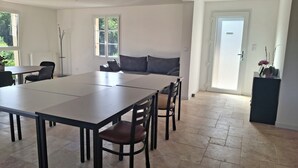 Une pièce spacieuse comprenant une grande table à manger, des chaises, un canapé et une porte donnant sur l’extérieur.