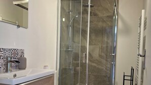 Une salle de bain moderne avec une douche à parois de verre, des toilettes blanches et un meuble-lavabo en bois.