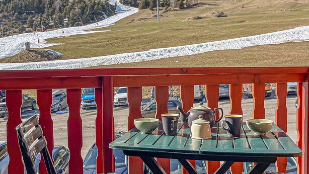 Ein Tisch mit Tassen und einem Wasserkocher auf einem Balkon mit Blick auf die Berge.