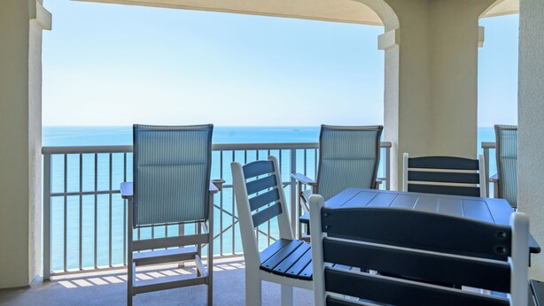 Een balkon met twee stoelen en een tafel, met uitzicht op zee.