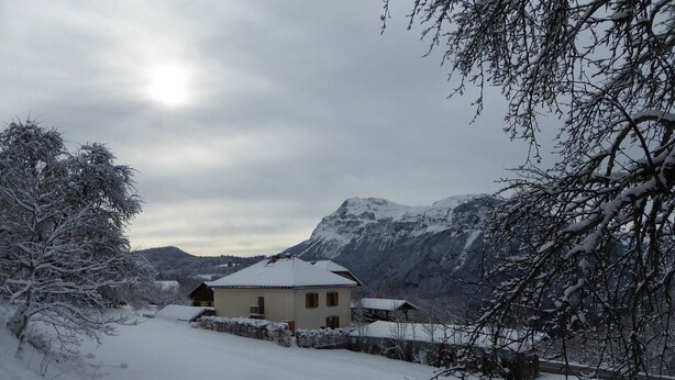 A snow-covered house with a mountain backdrop. - Apartment with parking, pets welcome - 8 guests (Arâches-la-Frasse)